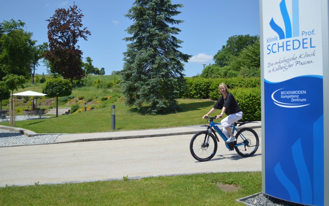 Bild E-Bike-Leasing - Mitarbeiterin die fröhlich mit ihrem E-Bike zur Arbeit kommt